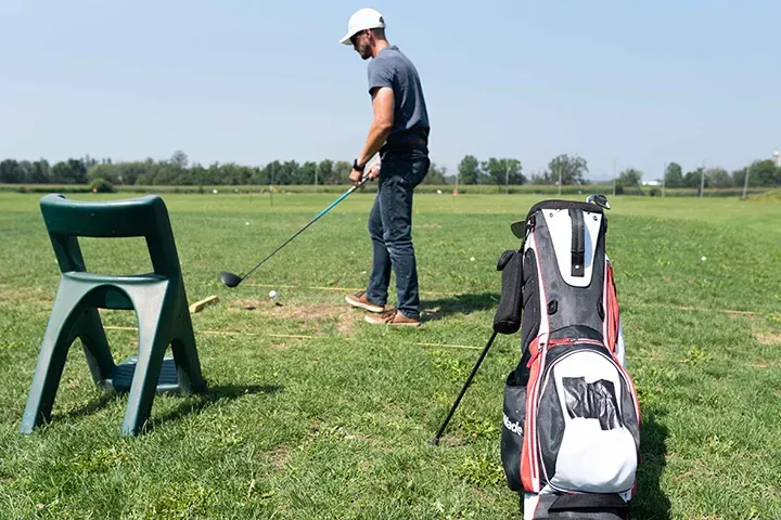 A man gets ready to tee off on the natural grass driving range at Market Sports.