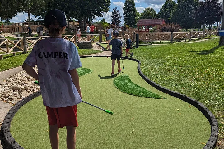 A young boy practices his putting on the Mini Golf course at Market Sports.